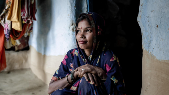 A Nepalese woman sitting in front of a wall and looking outside