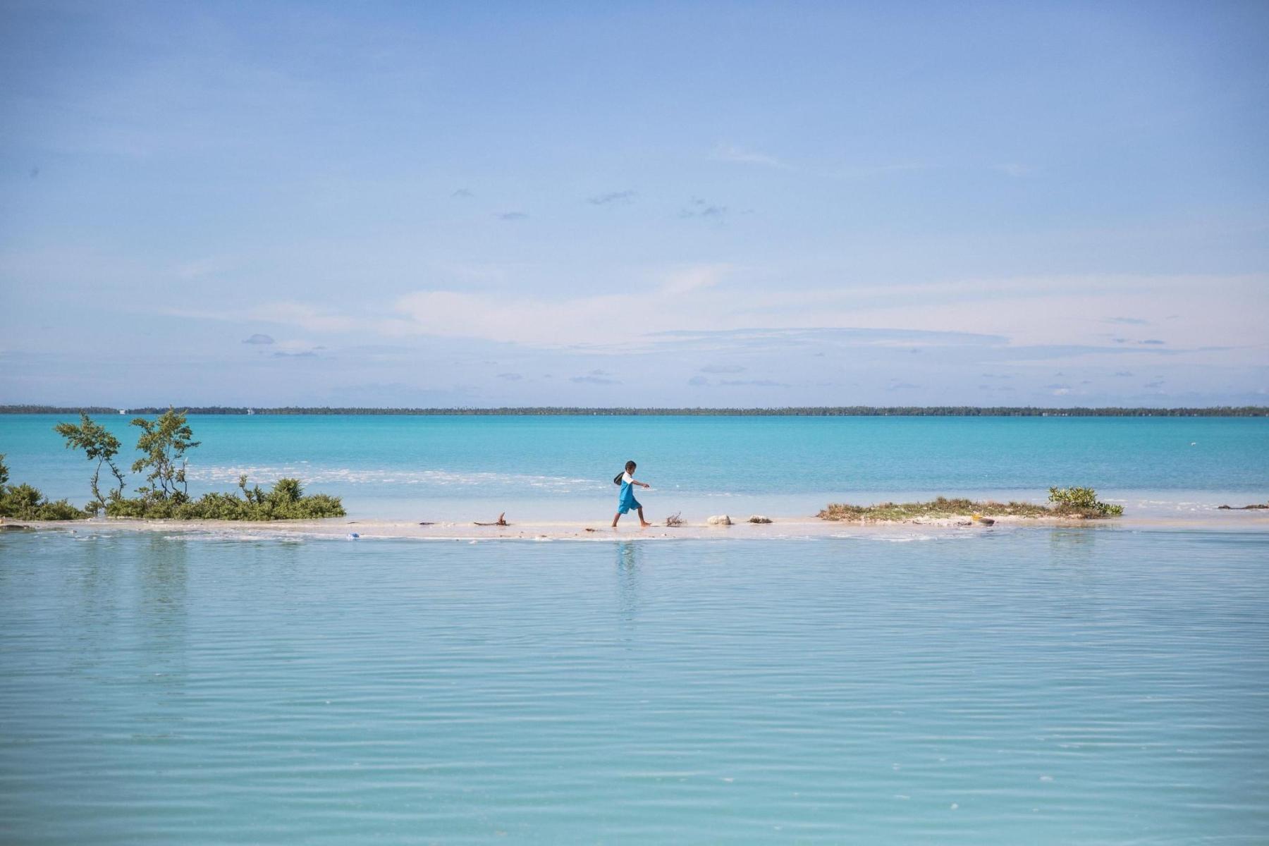A child walking along a narrow piece of land between two bodies of water